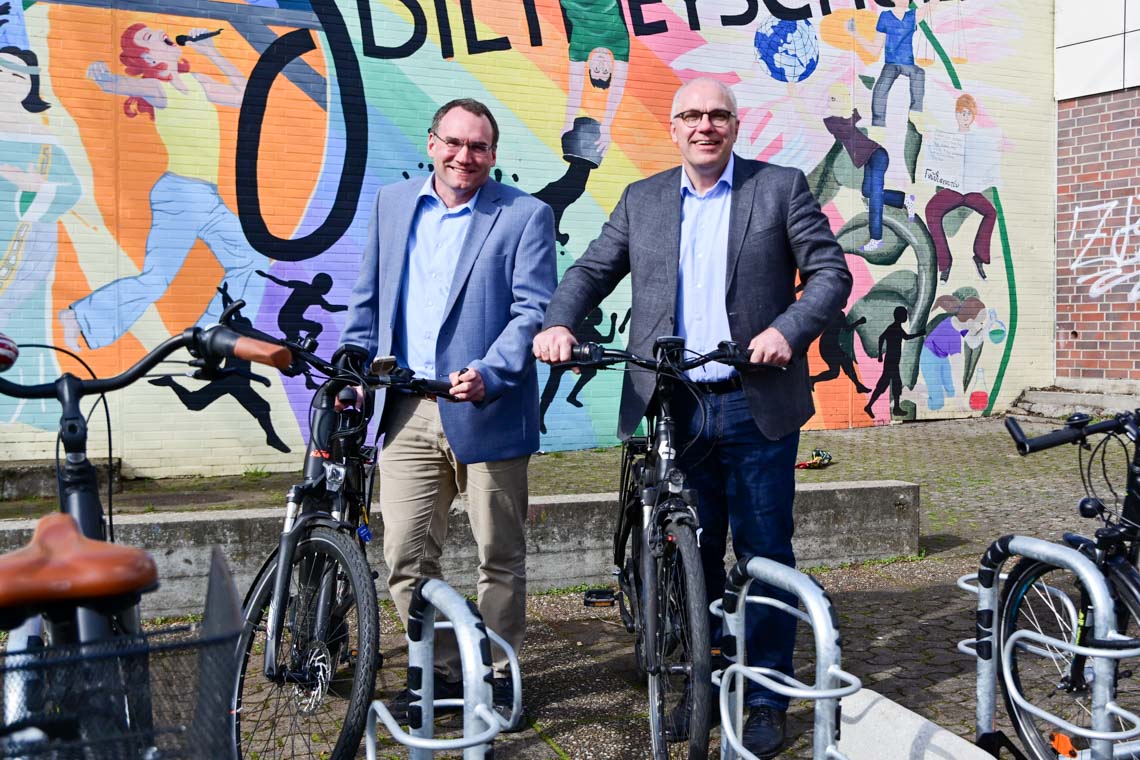 Schulleiter Jörg Schulte (re) und sein Stellvertreter Dr. Frank Becker stellen Räder in den neuen Fahrradständer.