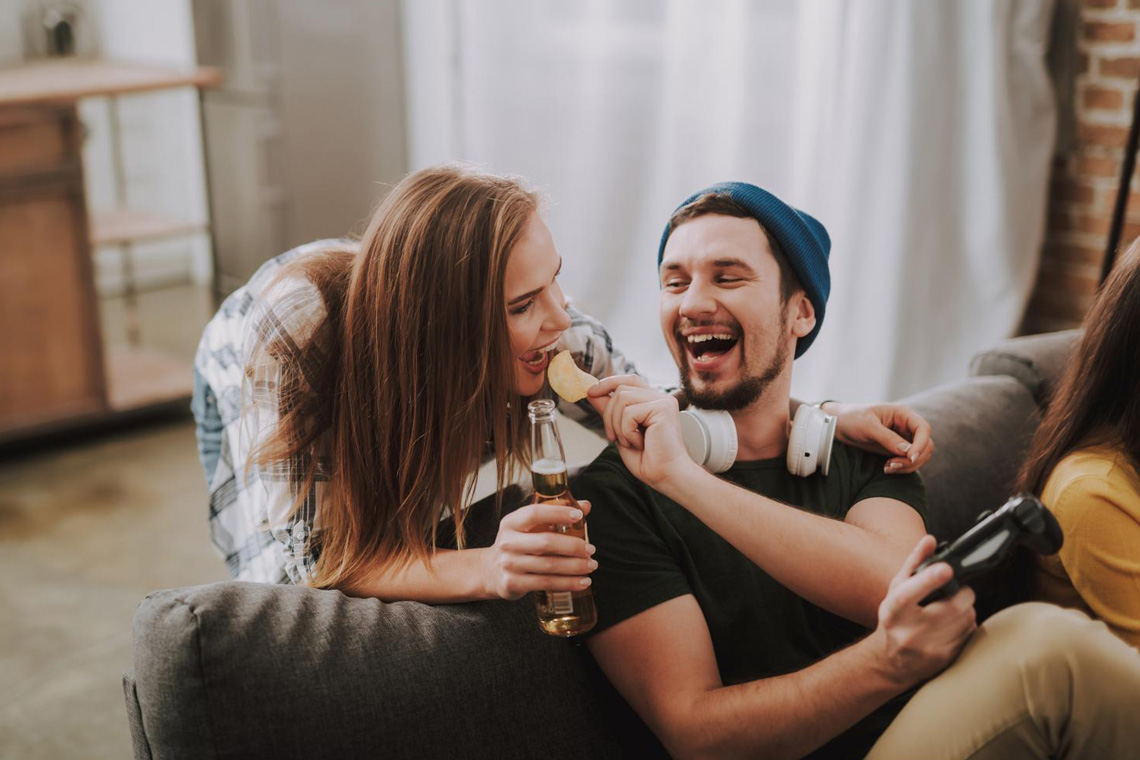 Freund sitz auf der Couch und füttert Freundin. Couch