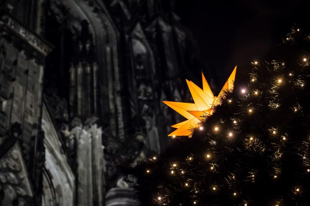 Kirche im Hintergrund mit Weihnachtsstern und Tannenbaum vorne. ©2022 Pixabay
