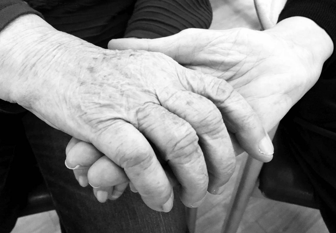 Zwei Hände geben sich die Hand: alt und jung. Generationenbild.