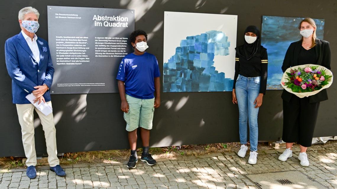 Bauzaun-Ausstellung Abstraktion im Quadrat Daria Capraro, Marianna Bartnicka von der Jawlensky Schule hängen das letzte Bild „Die Welle“ auf und eröffnen damit zusammen mit Rheinhard Ernst (links) und Carolin Langer die Ausstellung. Foto: Volker Watschounek