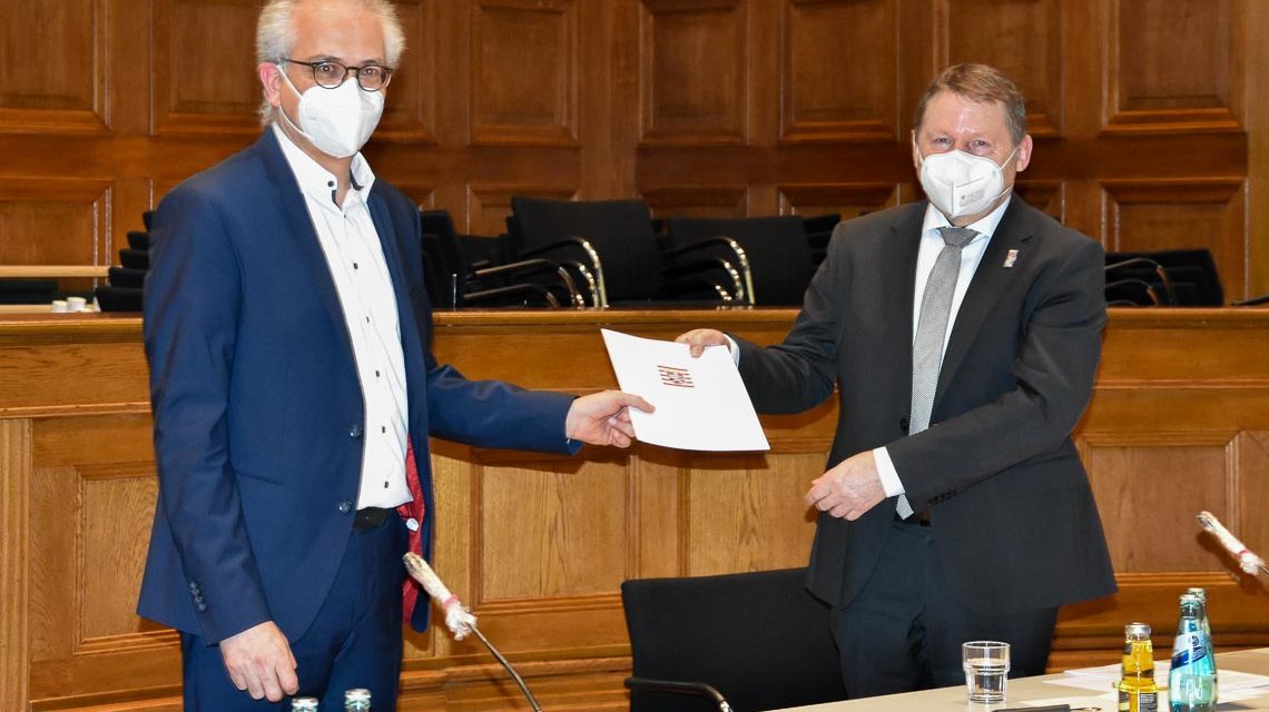 Bildunterschrift: Der hessische Minister für Wirtschaft, Ernergie, Verkehr und Wohnen Tarek Al-Wazir (links) überreicht dem Präsidenten von Hessen Mobil Prof. Gerd Riegelhuth die Abschiedsurkunde. Foto: Hessen Mobil