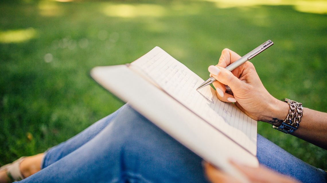 Frau schreibt im Grünen in ein Buch. Kreatives Schreiben Foto: StockSnap Pixabay