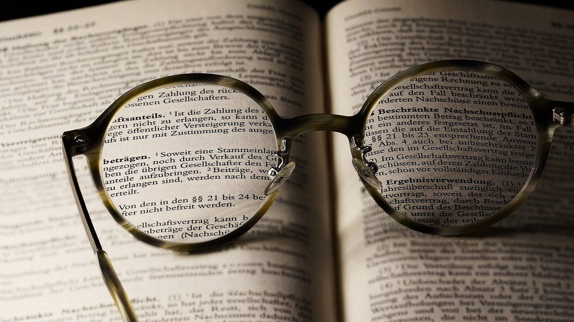 aufgeschlagenes Buch mit Brille, die Buchstaben verdeutlich. Literarische Mittagspause