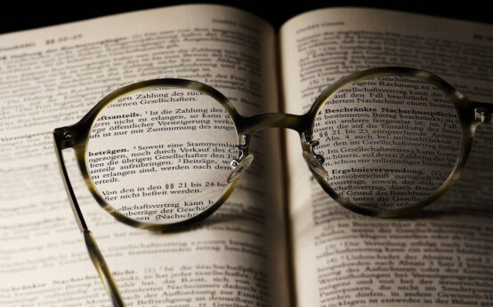 aufgeschlagenes Buch mit Brille, die Buchstaben verdeutlich. Literarische Mittagspause