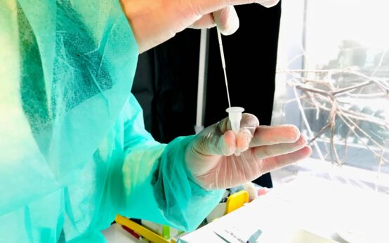 Apotheke: Schnelltest, der Tupfer wird eben in der Lösung gemäß den Vorgaben zehnmal nach rechts und dann nach links gedreht.