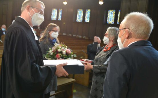 Wein und Blumen zum Abschied: Eberhard Busch (vorne rechts), Vorsitzender des Dekanatssynodalvorstands, und Präses Gabriele Schmidt verabschieden sich vom stellvertretenden Dekan Matthias Welsch (links) und seiner Frau (rechts daneben).