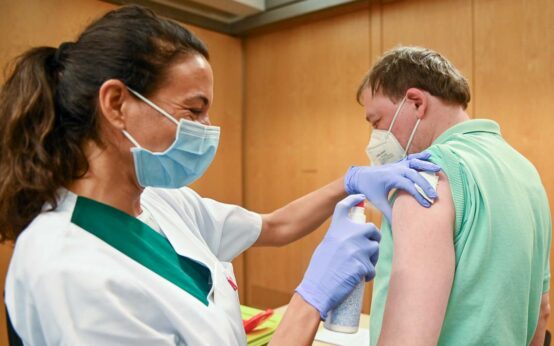 Betriebsarzt setzt die Spritze bei einem Mitarbeiter von Soka-Bau. (einrichtungsbezogene Impfpflicht)