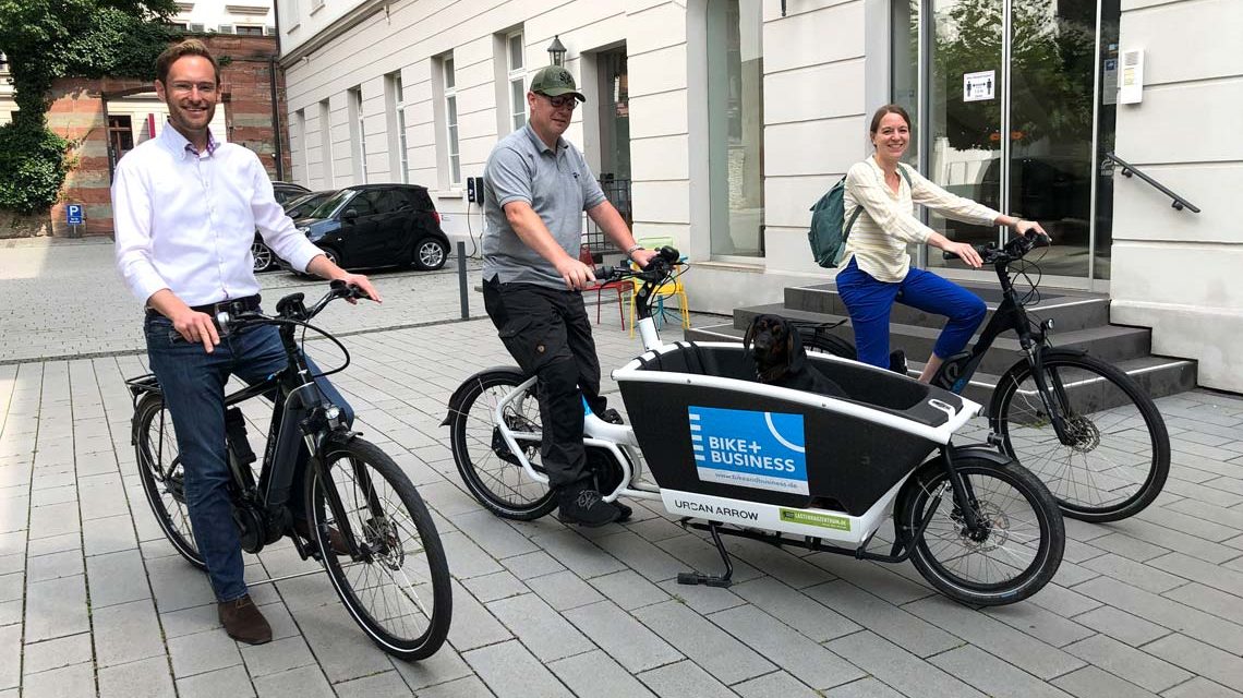 Felix Pohl, Jean Amend mit Hund Agilo und Christina Schröder aus dem IHK-Team bei der Übernahme der Räder. ©2021 IHK Wiesbaden