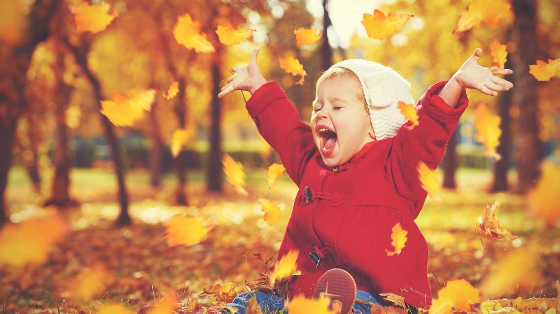 Herbst, Herbstanfang, kleines Kind freut sich über bunte Blätter.