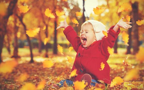 Herbst, Herbstanfang, kleines Kind freut sich über bunte Blätter.