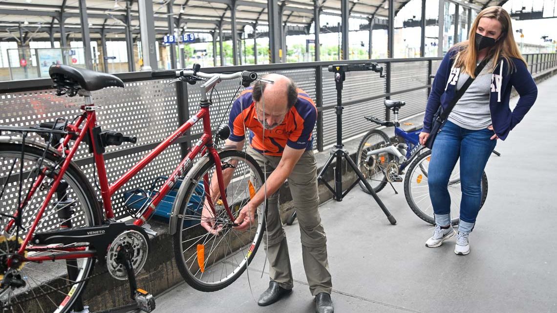 Der Radler, Mann baut an einem Fahrrad das Vorderrad aus.