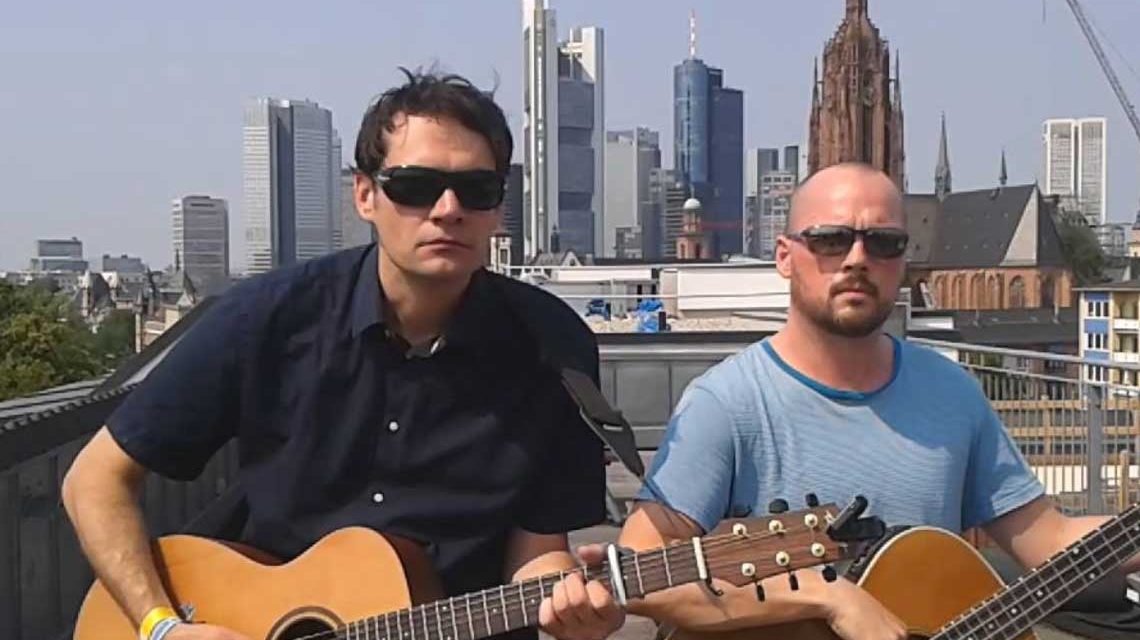 Tilman Birr und Elis singen Welthits auf Hessisch vor der Frankfurter Skyline.