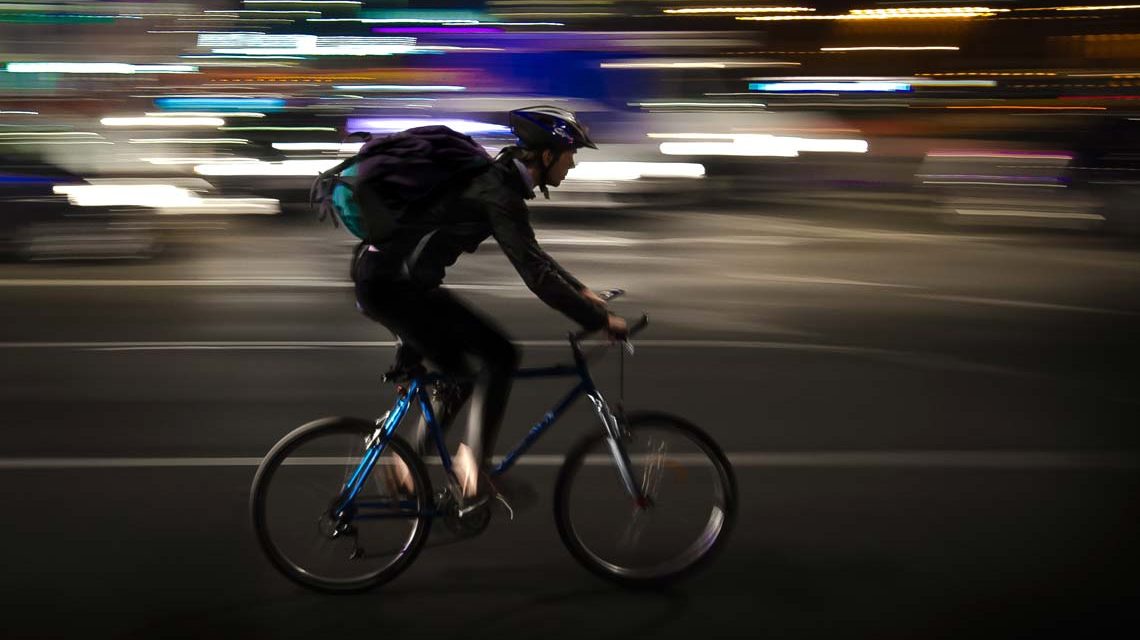 Radfahren in der Nacht, Fahrradfahrer auf einer belebten Straße.