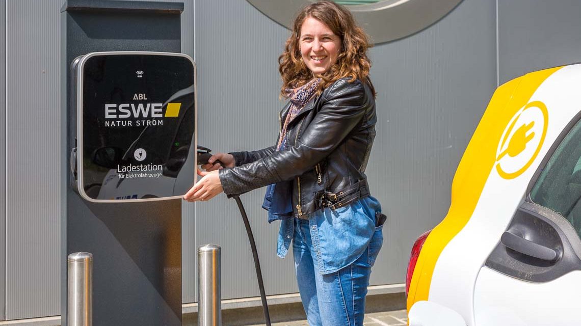 Frau tankt Strom an einer Stromtankstelle.