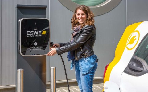 Frau tankt Strom an einer Stromtankstelle.