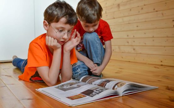 Kinder liegen auf dem Boden und lesen ein Buch