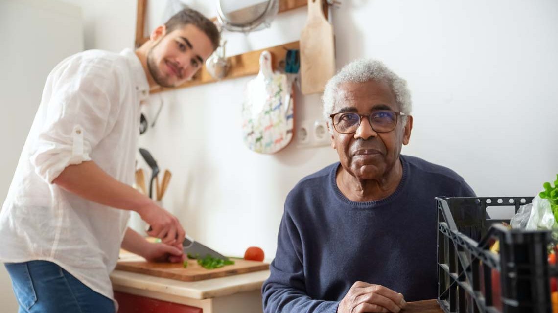 Junger Mann hilft einem älteren in der Küche: Freiwilliges Soziales Jahr