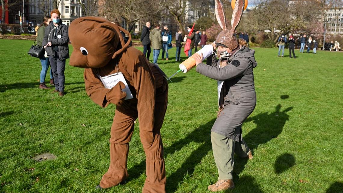 Ein Elefant bekommt von einem Osterhasen eine Spritze verpasst: Aktion der Impfkritiker
