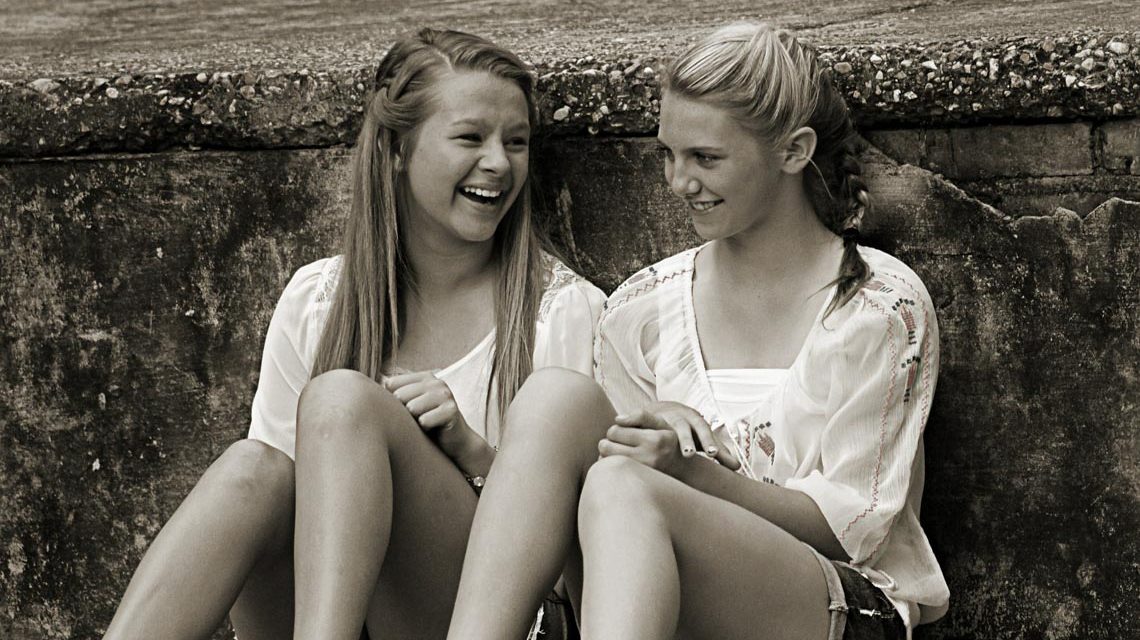 Zwei Mädchen chillen an einer Mauer