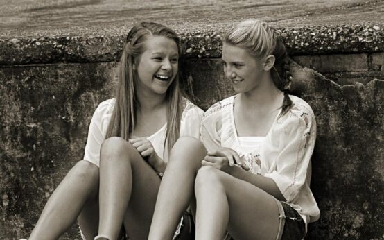 Zwei Mädchen chillen an einer Mauer