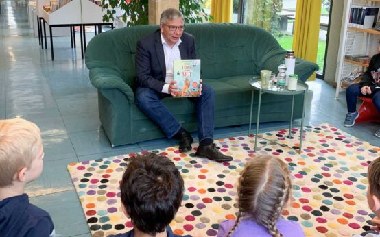 Vorlesetag in Wiesabden: Gert-Uwe Mende sitz auf dem Sofa und liest.