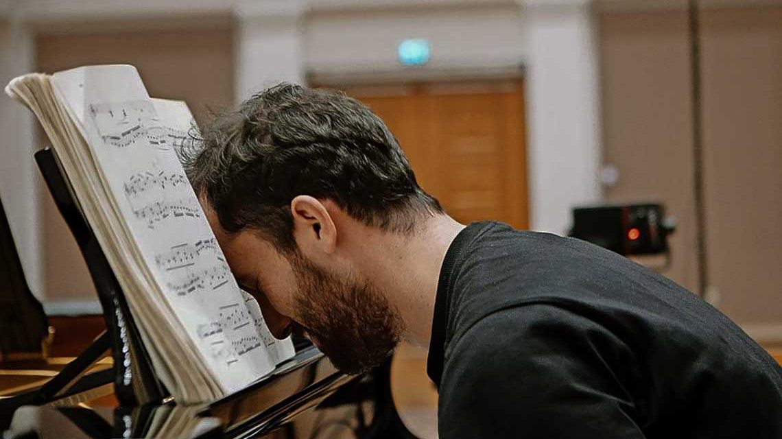 Igor-Levit sitzt am Klavier und vergräbt seinen Kopf in Noten.