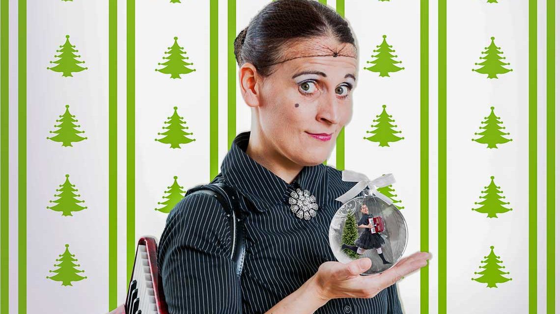 CARMELA DE FEO vor einer Weihnachtstapete mit Weihnachtskugel.