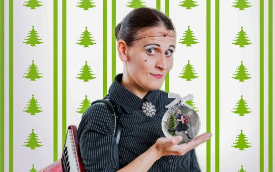 CARMELA DE FEO vor einer Weihnachtstapete mit Weihnachtskugel.