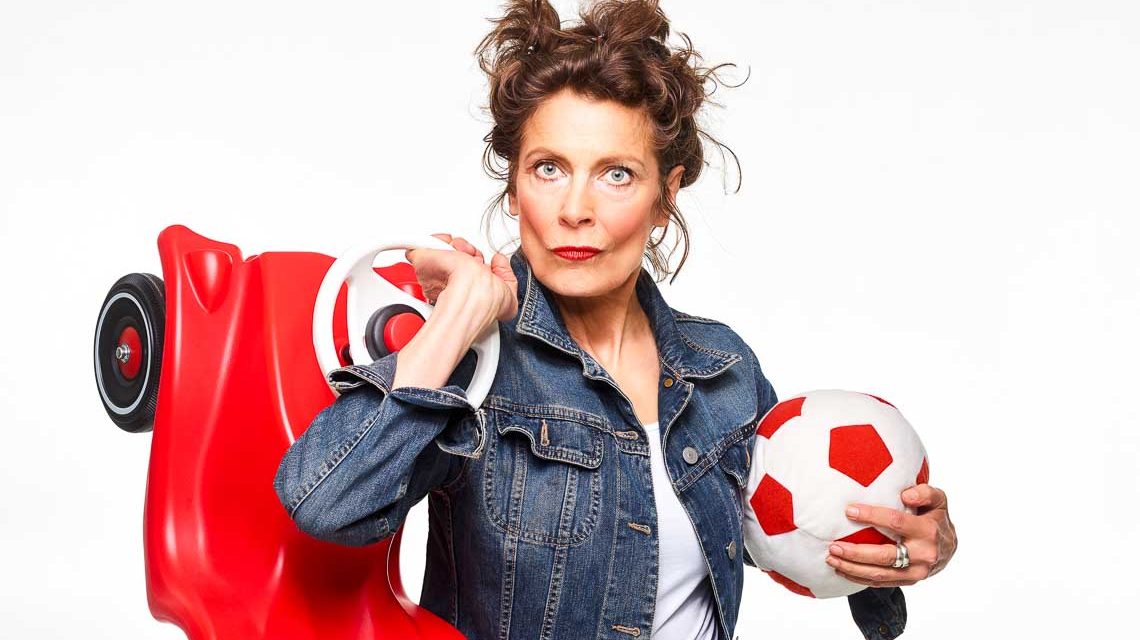 Frau, Madeleine Sauveur, mit Fußball im Arm und Bobby Car auf dem Rücken.