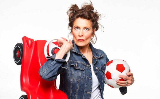 Frau, Madeleine Sauveur, mit Fußball im Arm und Bobby Car auf dem Rücken.