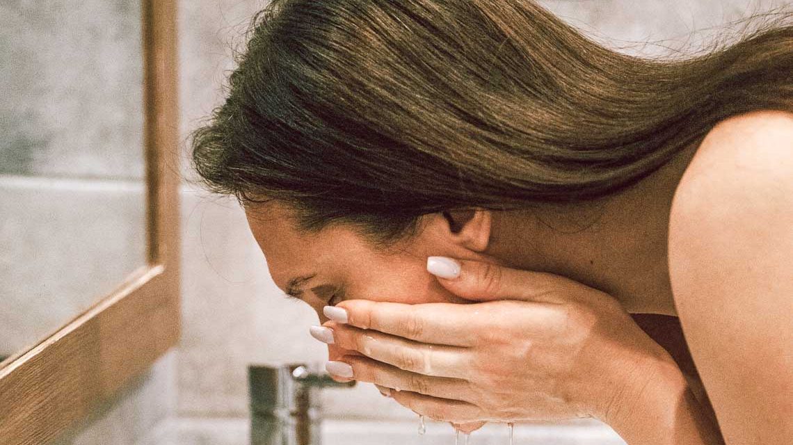 Hautpflege, Frau wäscht sich mit Wasser das Gesicht.