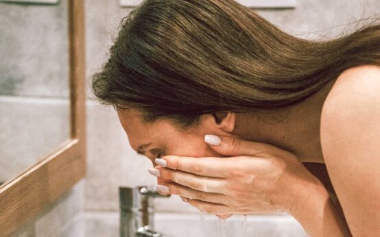 Hautpflege, Frau wäscht sich mit Wasser das Gesicht.