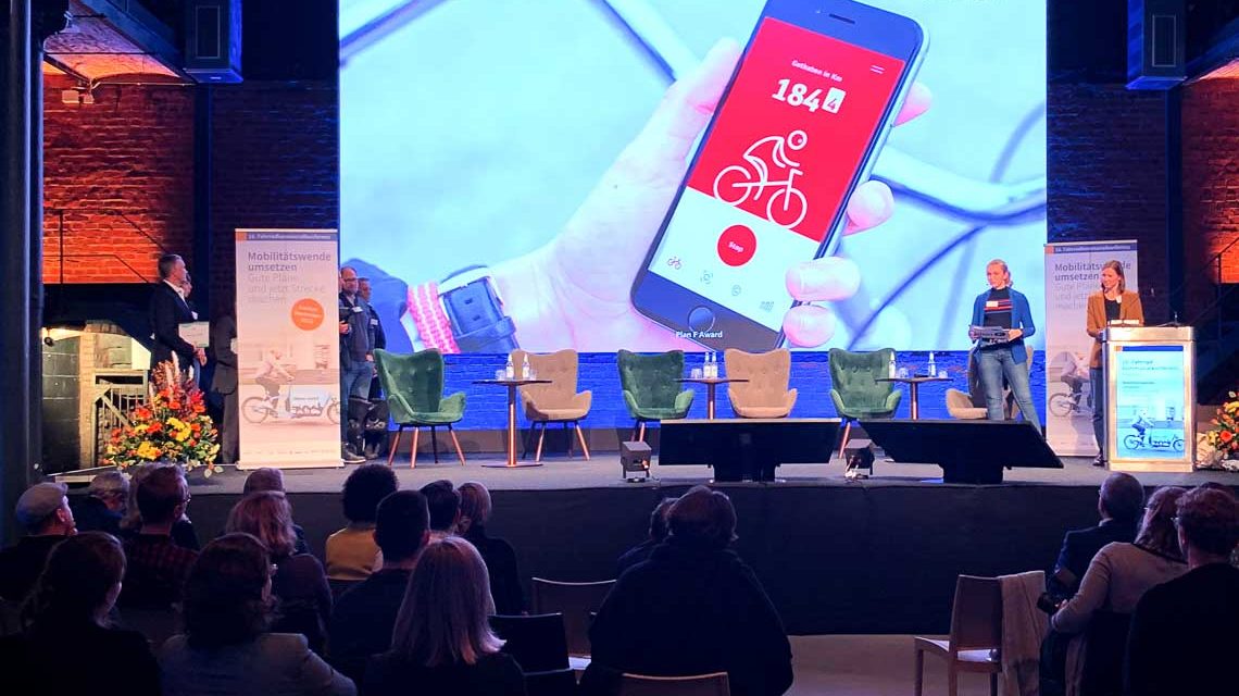 Bühne mit Leinwand, Die App wird darauf angezeigt. Preisverleihung des Plan F-Award.