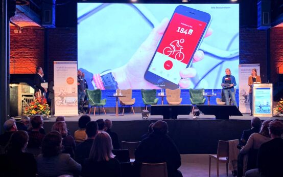 Bühne mit Leinwand, Die App wird darauf angezeigt. Preisverleihung des Plan F-Award.