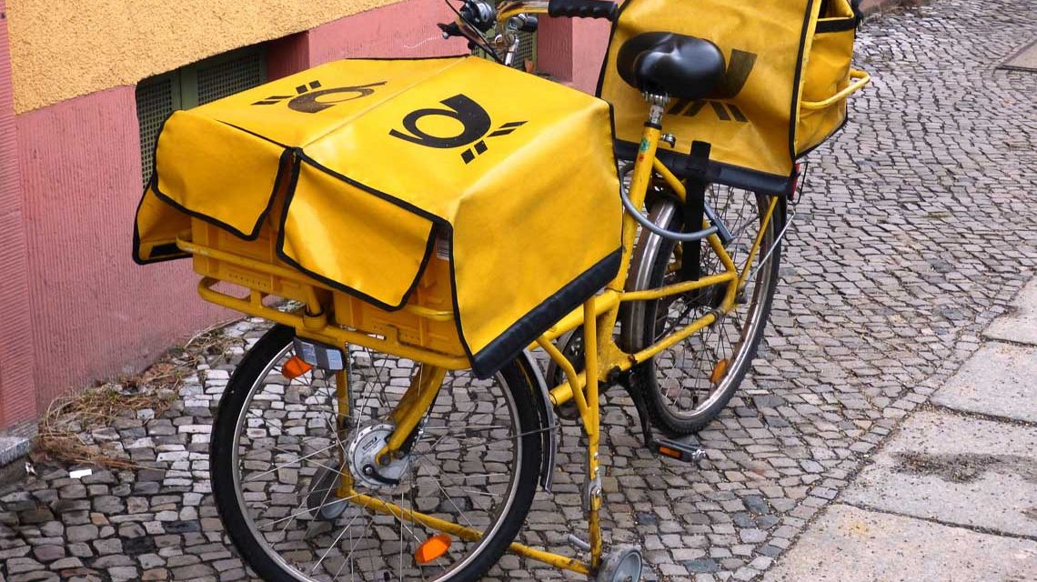 Fahrrad des Postboten auf der Straße vor einem Haus abgestellt.
