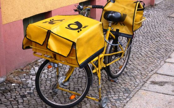 Fahrrad des Postboten auf der Straße vor einem Haus abgestellt.