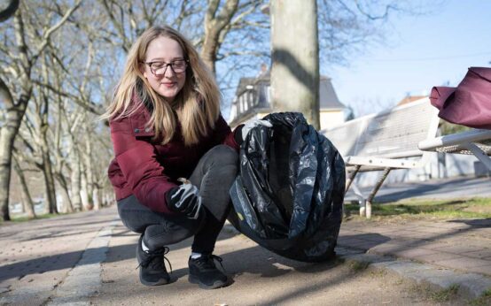 Schierstein räumt auf, junge Frau hebt Zigarettenkippen auf.