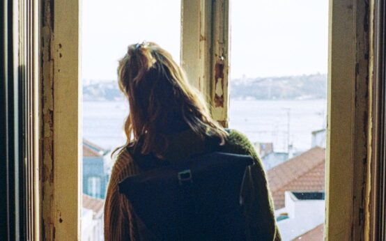 Frau schaut aus dem Fenster einer Sozialwohnung.