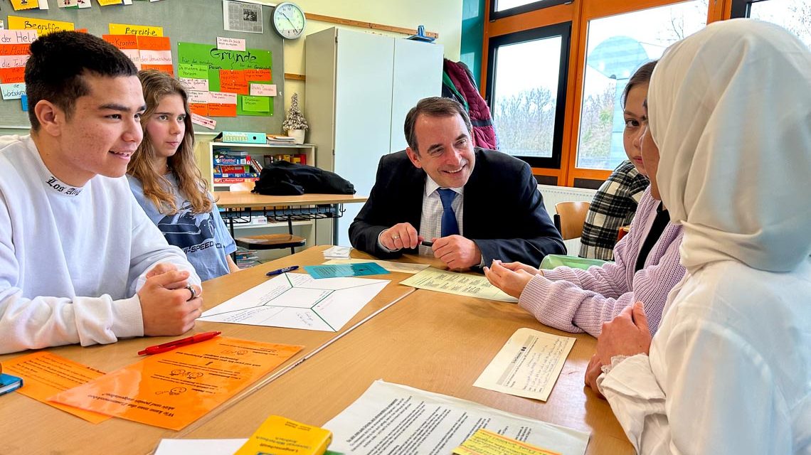 Minister Prof. Alexander Lorz mit Schülern an einem Tisch im Austausch. Förderung aus erster Hand.