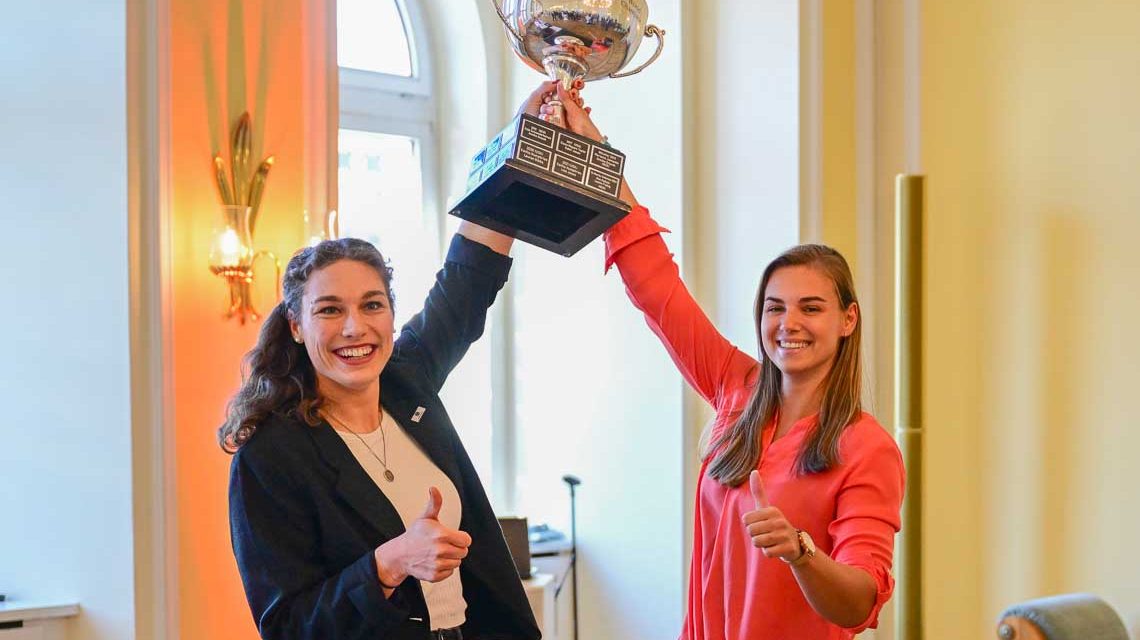 Die Wiesbadenerin Kim Kalicki und die Kölnerin Leonie Fiebig, Weltmeisterin im Zweiter-Bob strecken den Pokal empor.