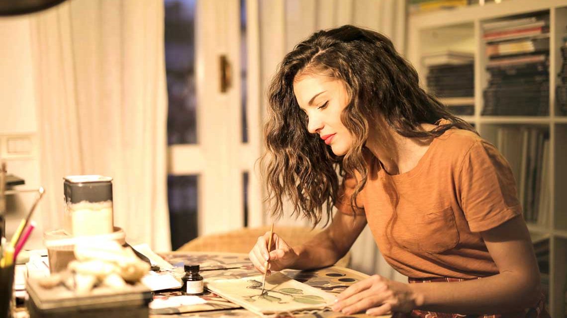 Jetzt das neue Glas zur Weinwoche gestalten: Junge Frau sitzt am Tisch und gestaltet einen Entwurf.