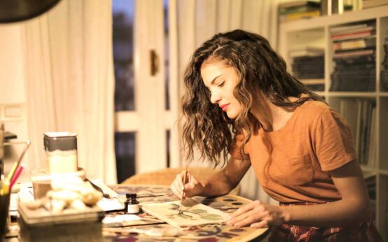 Jetzt das neue Glas zur Weinwoche gestalten: Junge Frau sitzt am Tisch und gestaltet einen Entwurf.