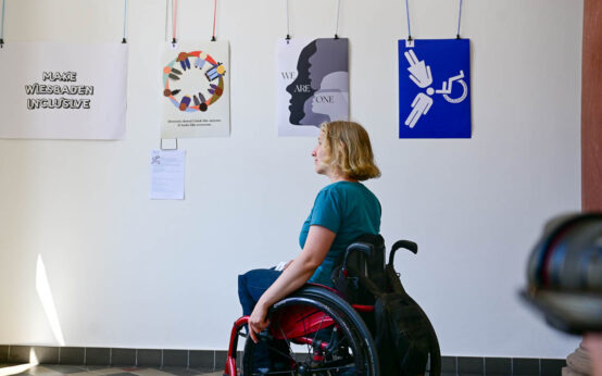 Frau im Rollstuhl schaut sich die Ausstellung „All inclusive" an.