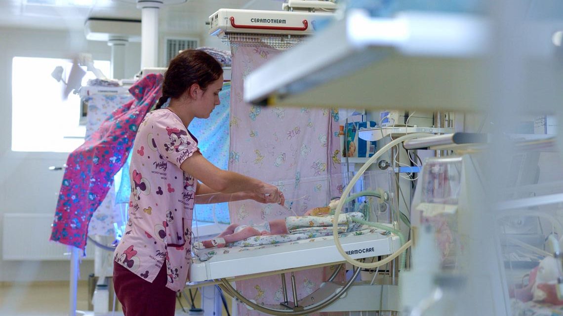 Schwester auf der Neugeborenenstation versorgt Baby: Pflegeberufe