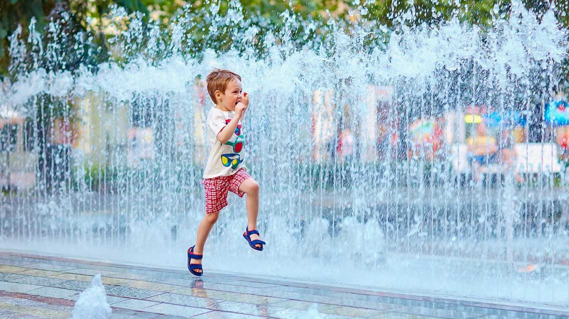 Klimaspaziergang, Kind läuft durch die >Stadt am Brunnen vorbei.