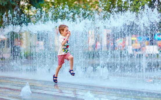 Klimaspaziergang, Kind läuft durch die >Stadt am Brunnen vorbei.