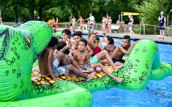 Wasserspieltage: Kinder auf aufblasbaren Spielgeräten im Becken eines Freibads