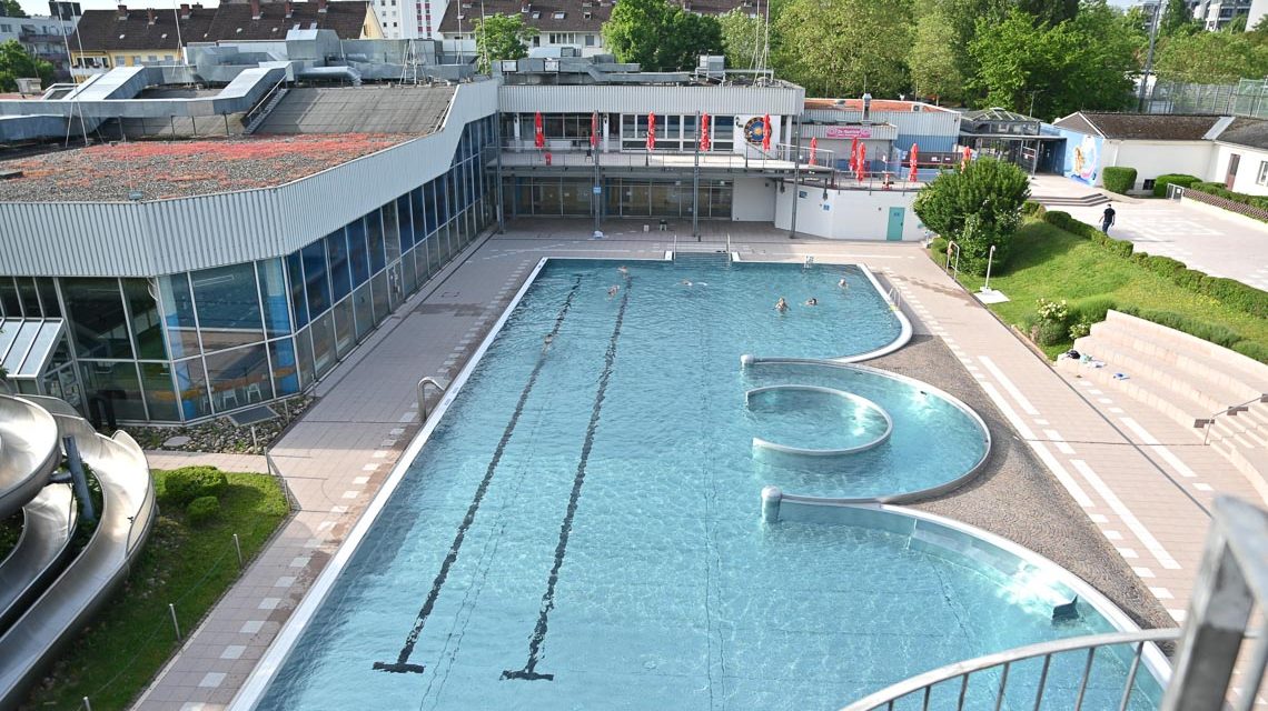 Blick auf leere Becken im Freibad Kleinfeldchen. Ein paar Schwimmer verlieren sich.