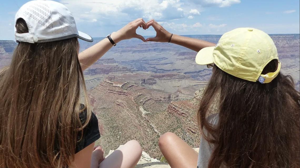 Zwei Schüler sitzen irgendwo in den USA auf einen Felsen und blicken in die Ferne. Mit den Händen formen sie ein Herz: Auf in die Welt-Messe!